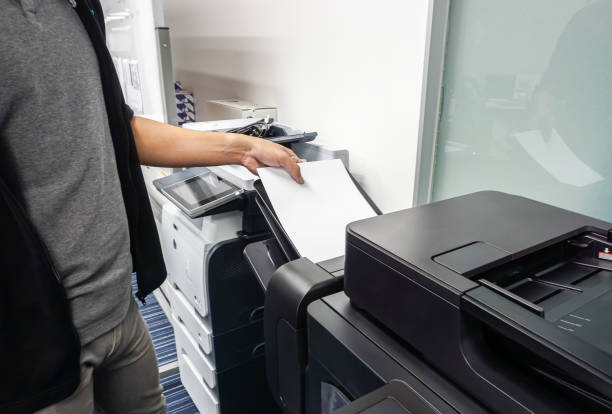 istock businessman put paper sheet into office printer tray for printing documents 864001860