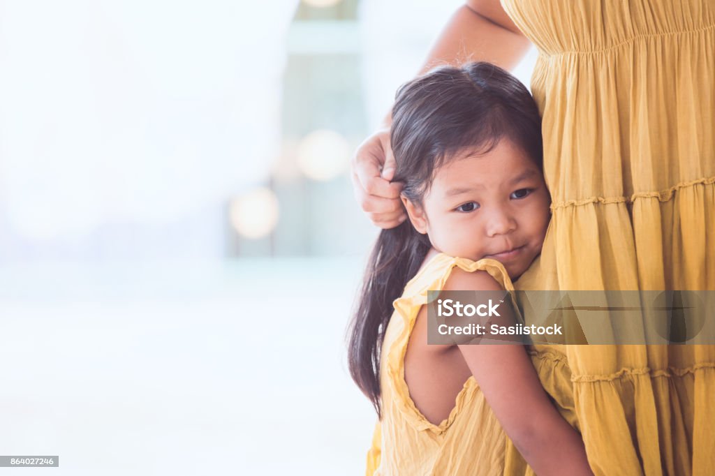 Sad asian child girl hugging her mother leg in vintage color tone Child Stock Photo
