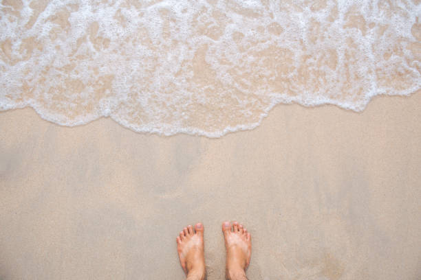 istock Sea wave movement with feet and sand. 864029692