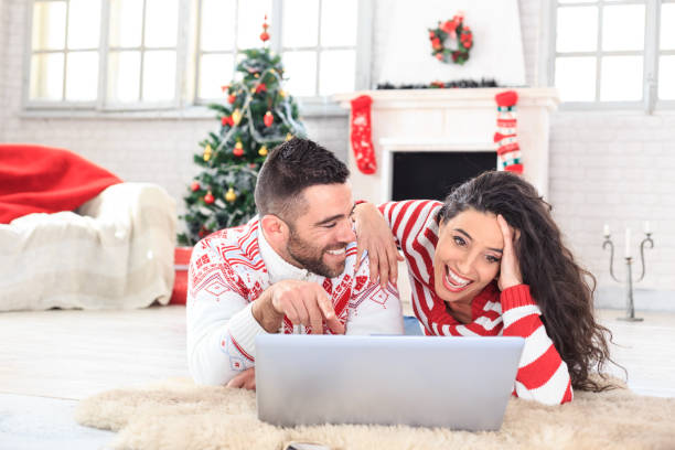 souriante jeune couple couché et à l’aide d’ordinateur portable à la maison - global warming flash photos et images de collection