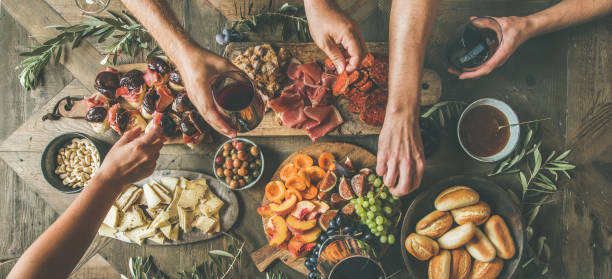 Top view of people having party, gathering, celebrating together Flat-lay of friends hands eating and drinking together. Top view of people having party, gathering, celebrating together at wooden rustic table set with different wine snacks and fingerfoods cheese wine food appetizer stock pictures, royalty-free photos & images