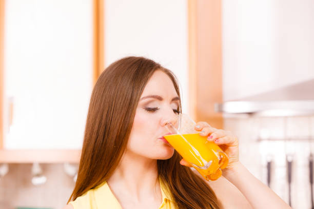 istock Woman in kitchen drinking fresh orange juice 864089704