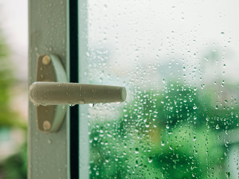 Raindrop on window with Handle Blur tree background Rainy Season