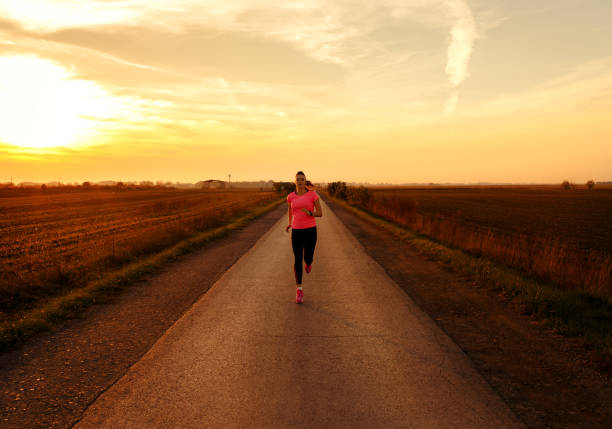 istock Athletic woman running on rural road during sunset. 864101622