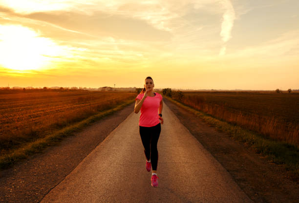 istock Athletic woman running on rural road during sunset. 864103836