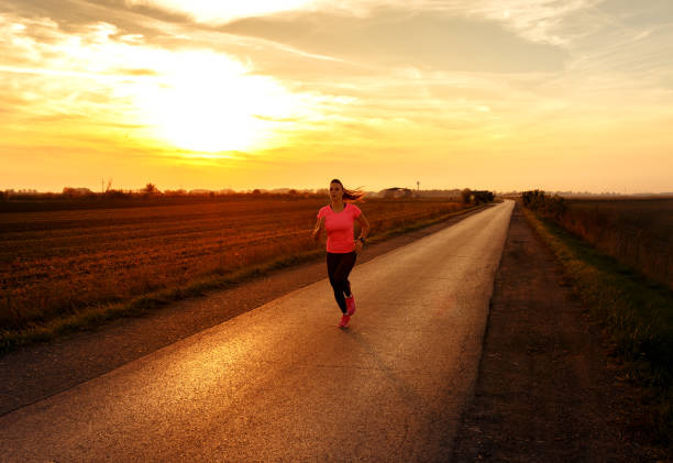 istock Athletic woman running on rural road during sunset. 864103886