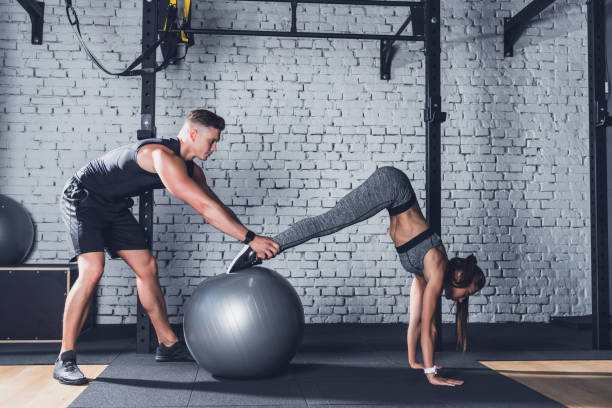 istock trainer helping woman work out 864129222