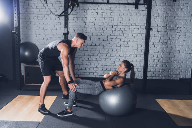 istock trainer helping woman work out 864132160