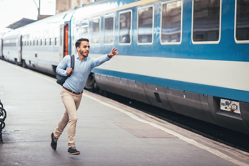 Portrait of Latin American young man in smart casual clothing, representing young businessman, entrepreneur or University student. Handsome Latino in blue shirt commuting to work and running after train.