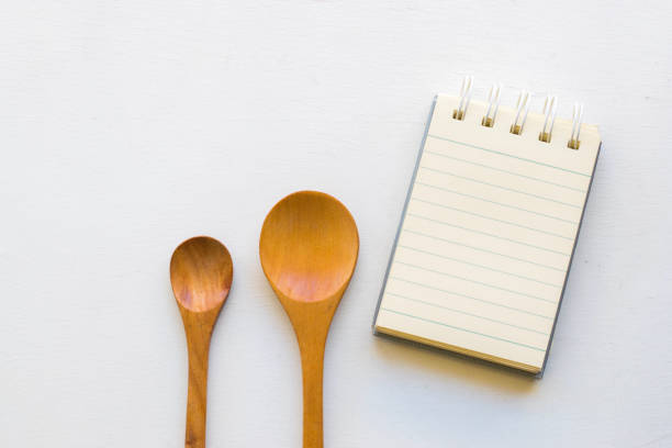 istock Notepad with spoons and vegetable on wood wood background.Using wallpaper for food, kitchen and cook composition image Take note product for book with paper and concept or copy space with note 864149788