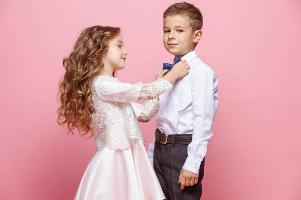 istock Boy and girl standing in studio on pink background 864154940