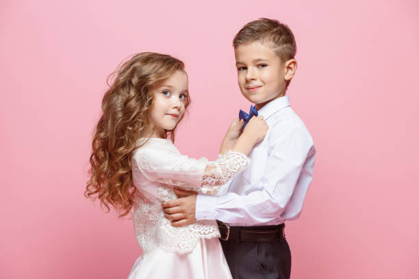 istock Boy and girl standing in studio on pink background 864155012