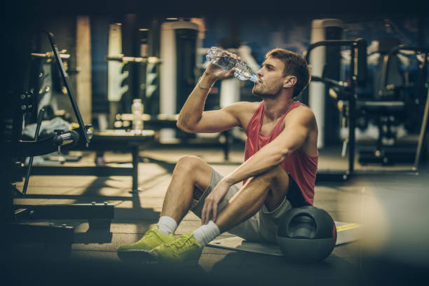 istock Thirsty athletic man drinking water on a break in a gym. 864158690