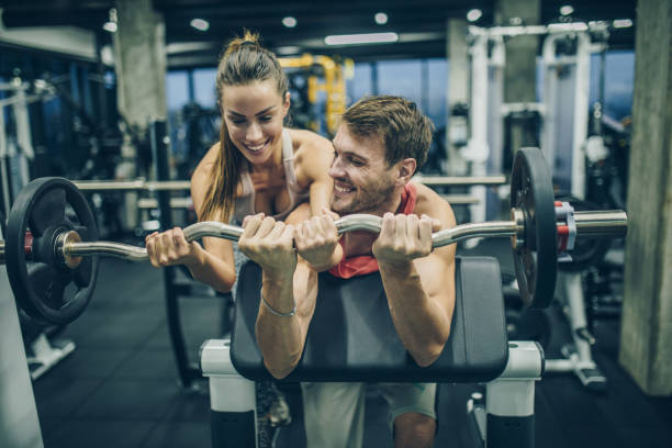 istock Happy athletic couple cooperating while exercising with barbell in a gym. 864161280