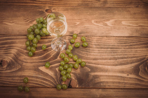 istock Glass of white wine and grapes on rustic wood table 864173216