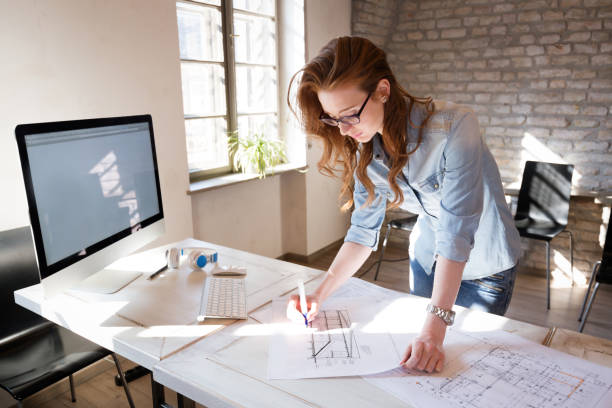 Female designer in office working on architects project Beautiful Female designer in office working on architects project architect office stock pictures, royalty-free photos & images