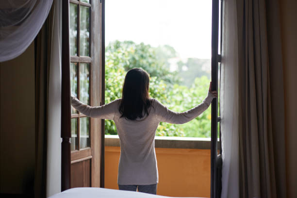 One more beautiful morning Rear view of young woman enjoying view from balcony of her room opening stock pictures, royalty-free photos & images