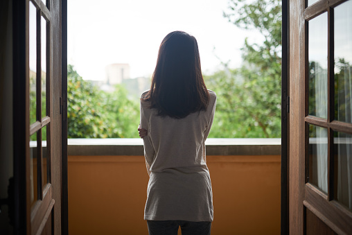 Rear view of woman standing on balcony and enjoying the view