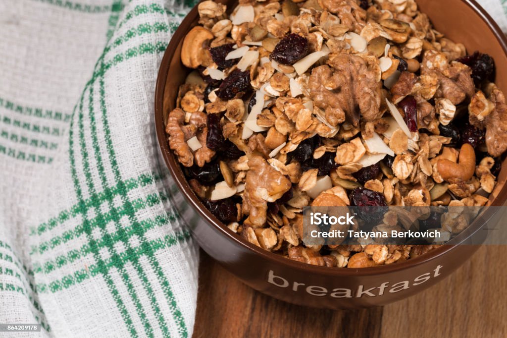 Homemade granola with honey, oatmeal, cashew nut, almond, pistachio, raisin and cranberry in clay bowl,glass with milk on wood dark table, Almond Stock Photo