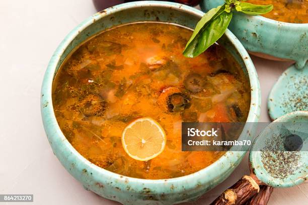 Soup With Meat Smoked Meat Sausages Pickled Cucumbers Tomatoes Olives Herbs Lemon In Blue Bowl On Gray Concrete Background Homemade Food Traditional Russian And Ukrainian Soup Solyanka Stock Photo - Download Image Now