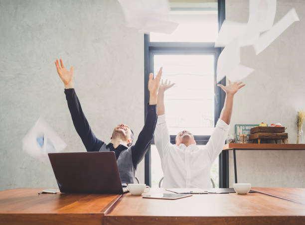 istock Two of young businessman trowing papers papers/sheets for work after finishing work, successful in business target in modern office, feeling happy, cheerful and relax 864217468