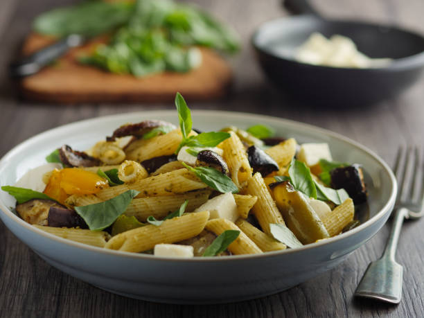 Roasted vegetable pasta salad Home made freshness roasted vegetable,aubergine,bell pepper and mushroom with pene pasta with green pesto sauce,service with mozzarella cheese and basil leaves. rigatoni stock pictures, royalty-free photos & images