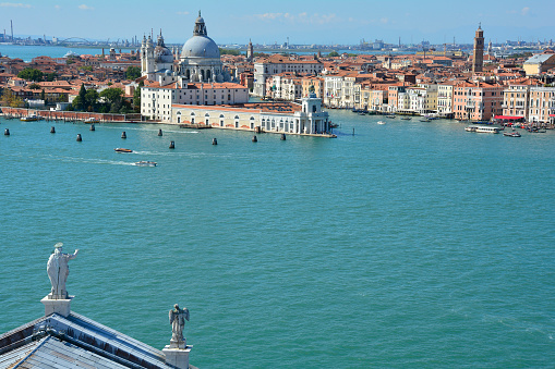 The view from the top of the bellltower of San Giorgio Maggiore church in Venice. Part of the church's roof can be seen in the foreground with Punta Della Dogana and the church of Santa Maria Della Salute (Saint Mary of Health) in the background.
