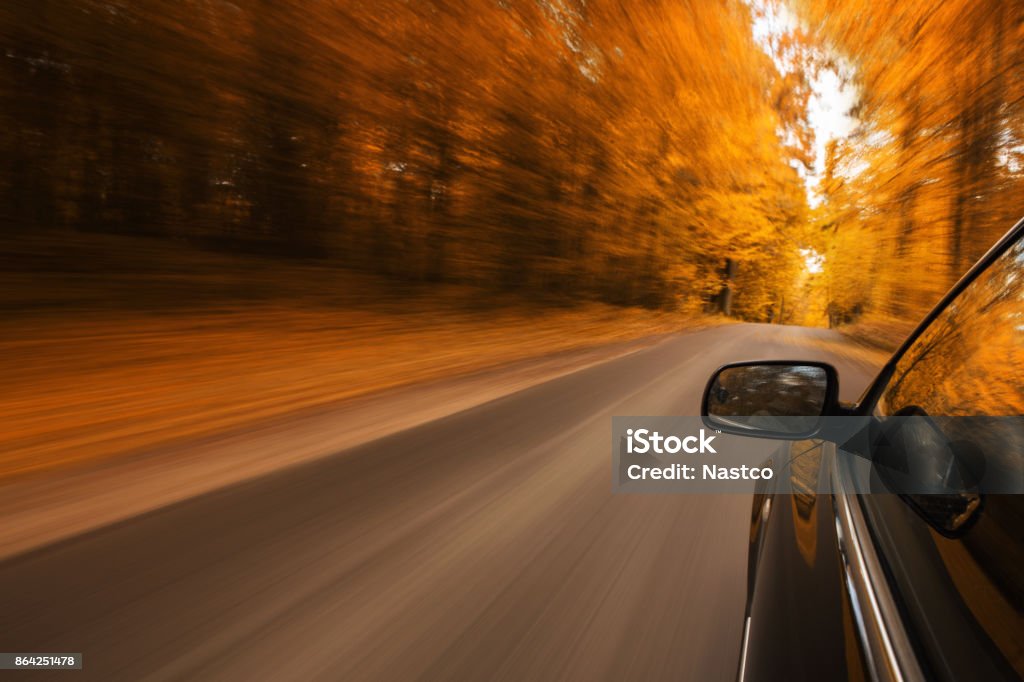 Car speeding on the road Close up of a sport car speeding on the empty, autumn road with copy space Car Stock Photo