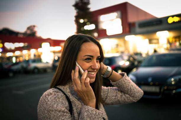 istock Smiling young woman using smart phone on streets by night 864251908
