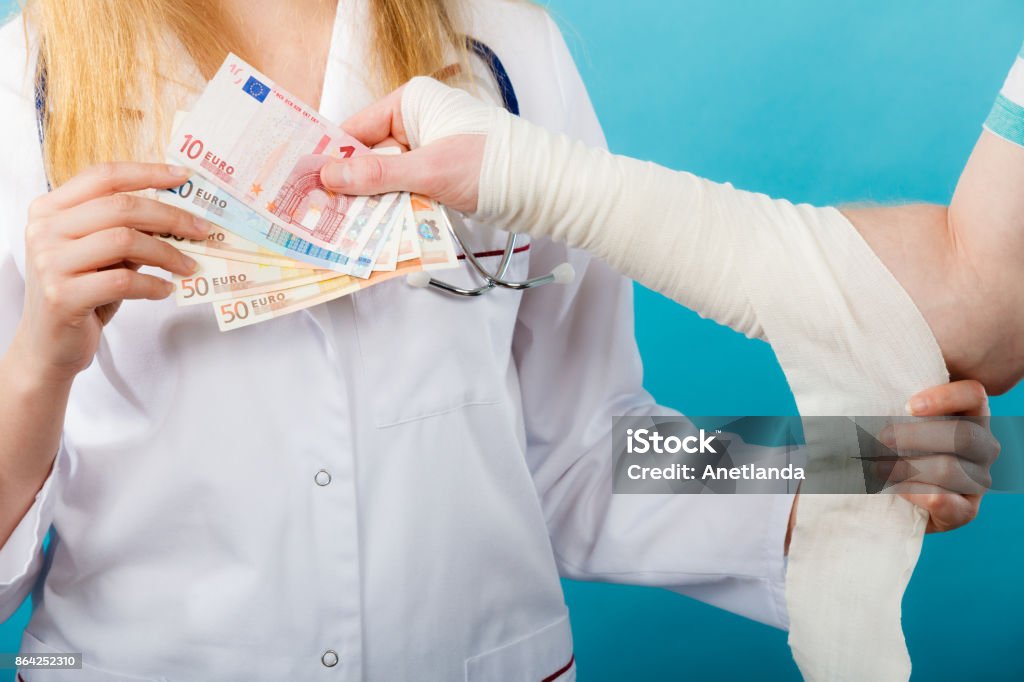 Female doctor bandaging male hand. Corruption in healthcare industry. Female doctor bandaging male hand. Man giving money to woman. Bribery in medicine. Adult Stock Photo