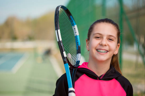 Young Girl With Braces Posing Young Girl With Braces Posing Holding A Tennis Racket cute 15 year old girls stock pictures, royalty-free photos & images