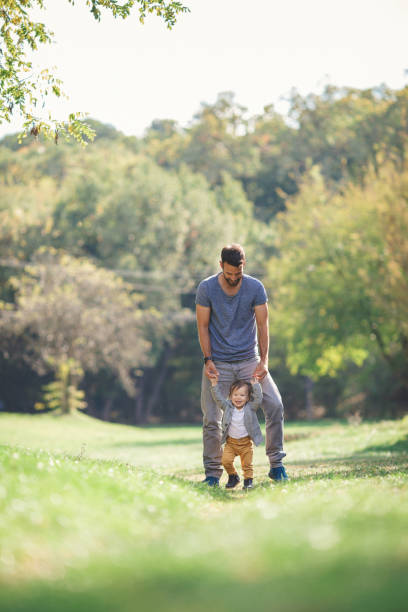 istock Young father teaching his baby boy to walk 864292408