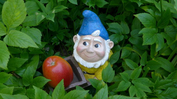 istock Funny garden dwarf on a green meadow with flowers 864292798