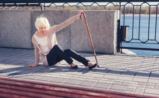 istock Elderly lady getting up after falling down in the street 864309004