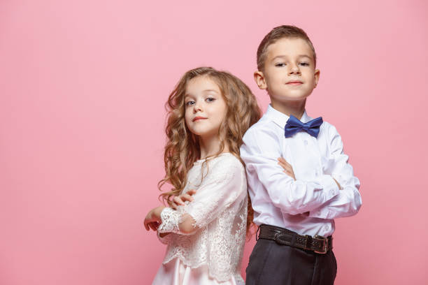 Boy and girl standing in studio on pink background