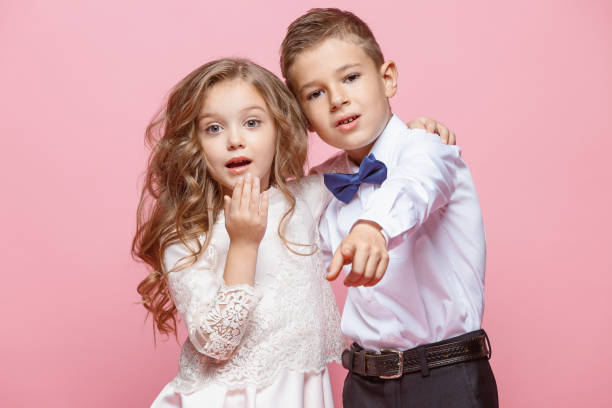 istock Boy and girl standing in studio on pink background 864313504