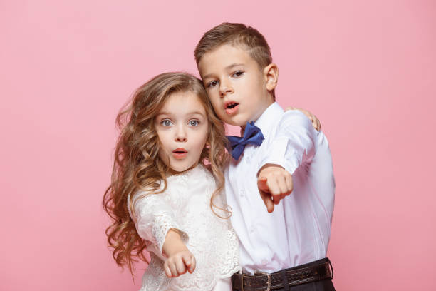 istock Boy and girl standing in studio on pink background 864313570