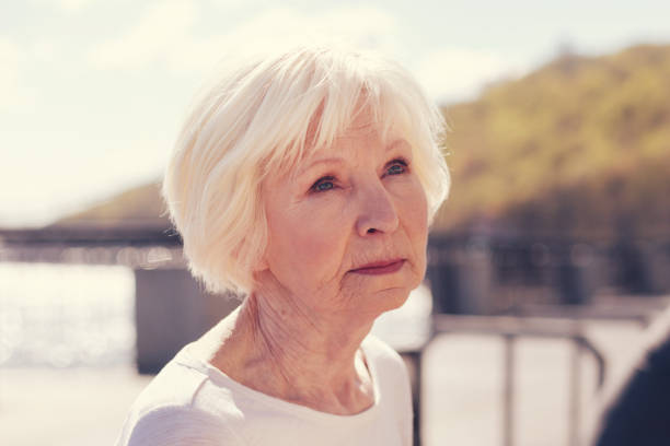 物欲しそうな表情で魅力的な年配の女性のクローズ アップ - grief women selective focus outdoors ストックフォトと画像