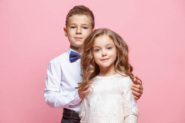 istock Boy and girl standing in studio on pink background 864316992