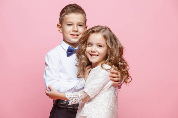 istock Boy and girl standing in studio on pink background 864317008