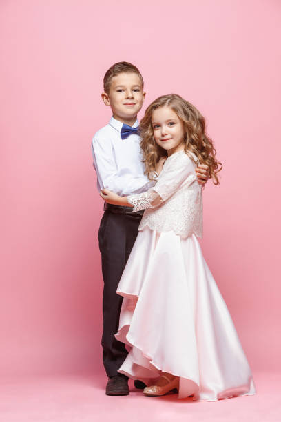 istock Boy and girl standing in studio on pink background 864319128