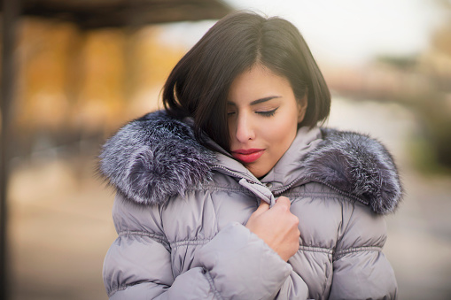 Portrait of a beautiful young woman wrapped up warm in furry winter jacket.