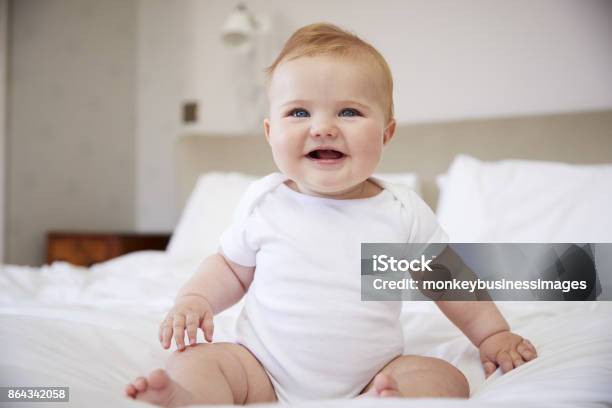 Happy Baby Boy Sitting On Parents Bed Stock Photo - Download Image Now - Baby - Human Age, Infant Bodysuit, White People