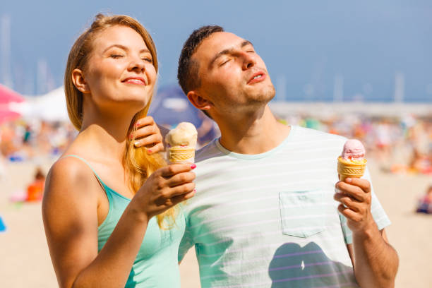 istock Man and woman eating ice cream on beach 864343020
