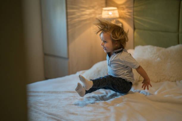 istock Cute boy jumping on the bed 864345574