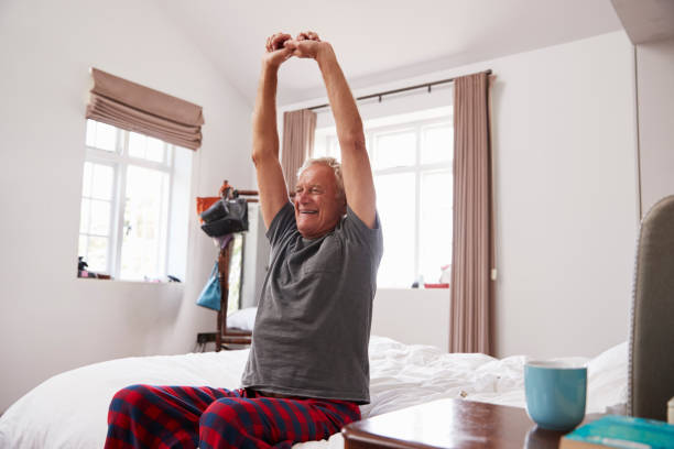 istock Senior Man Waking Up And Stretching In Bedroom 864345782