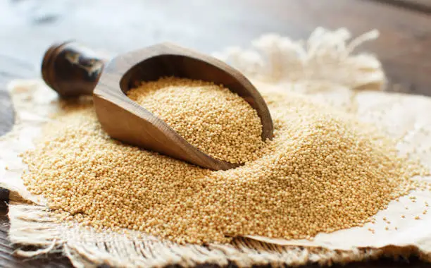 Raw Organic Amaranth grainwith a spoon on a wooden table