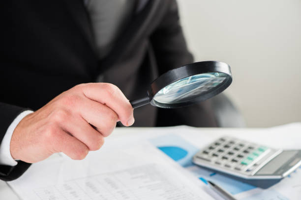 istock Businessman looking through a magnifying glass to documents 864352492