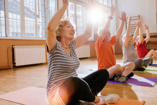 active seniors enjoying retirement group of cheerful seniors having fun together exercising yoga stock pictures, royalty-free photos & images