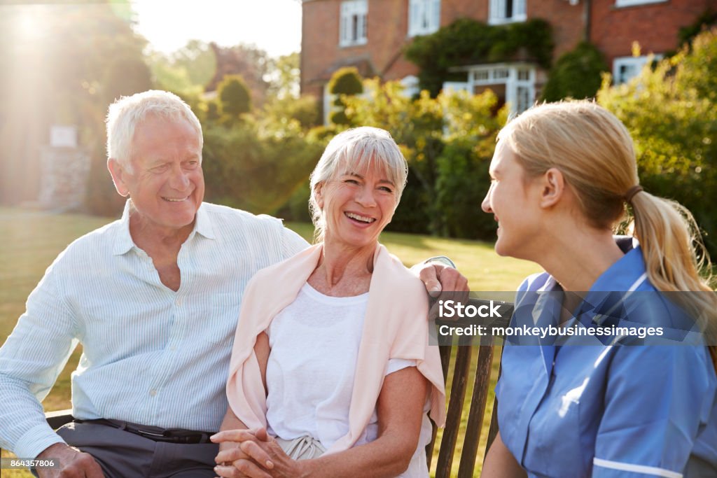 Nurse Talking To Senior Couple In Residential Care Home Retirement Community Stock Photo